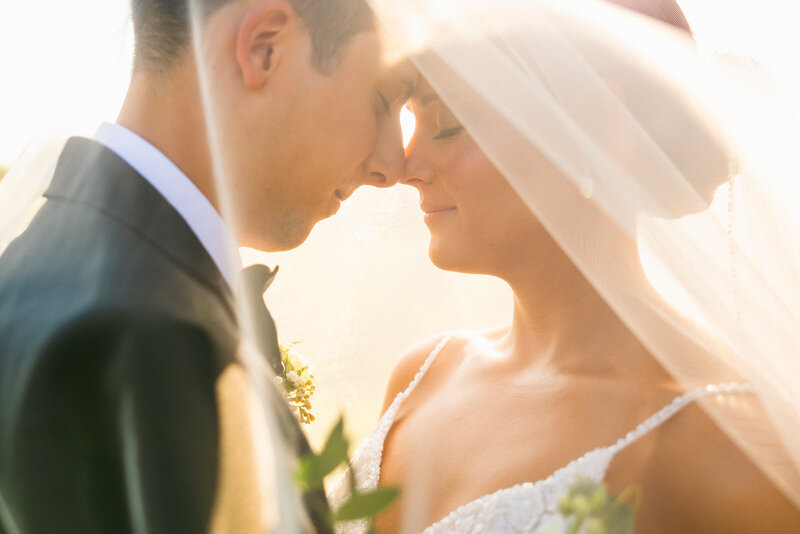 Warm image of bride and groom under veil at The White Dove Barn wedding