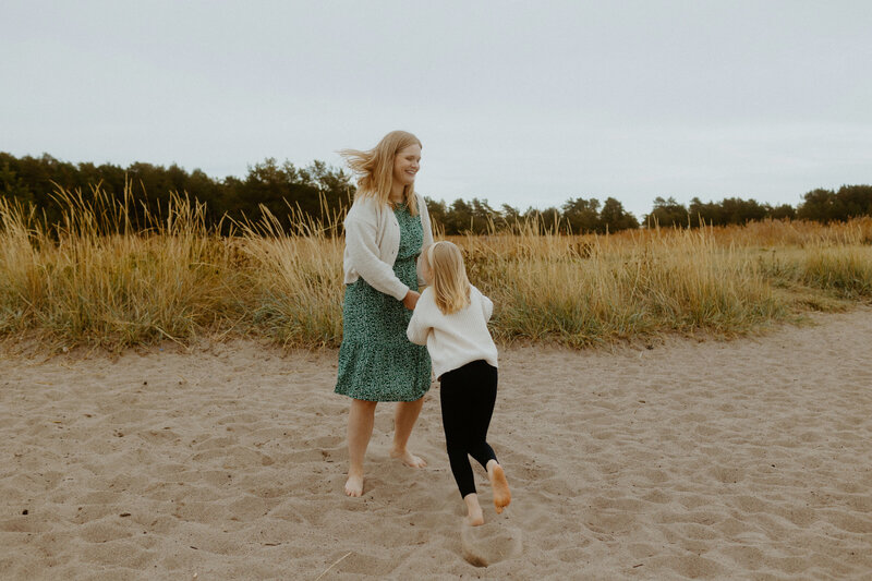 Perhekuvaus äidistä ja lapsesta kävelemässä käsi kädessä Kallahdessa Helsingissä.