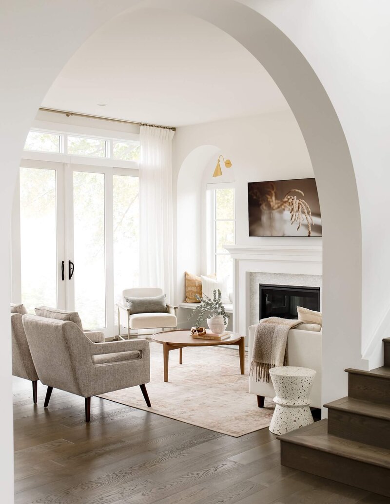 Arched living room with neutral upholsterly and custom drapery panels in sheer fabric. 