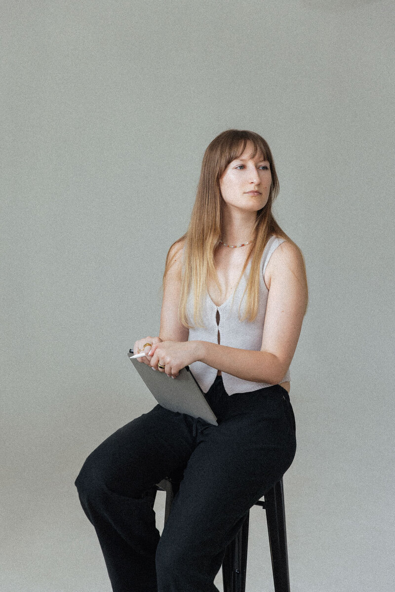Porträt von Anna, die sitzend mit einem iPad arbeitet.