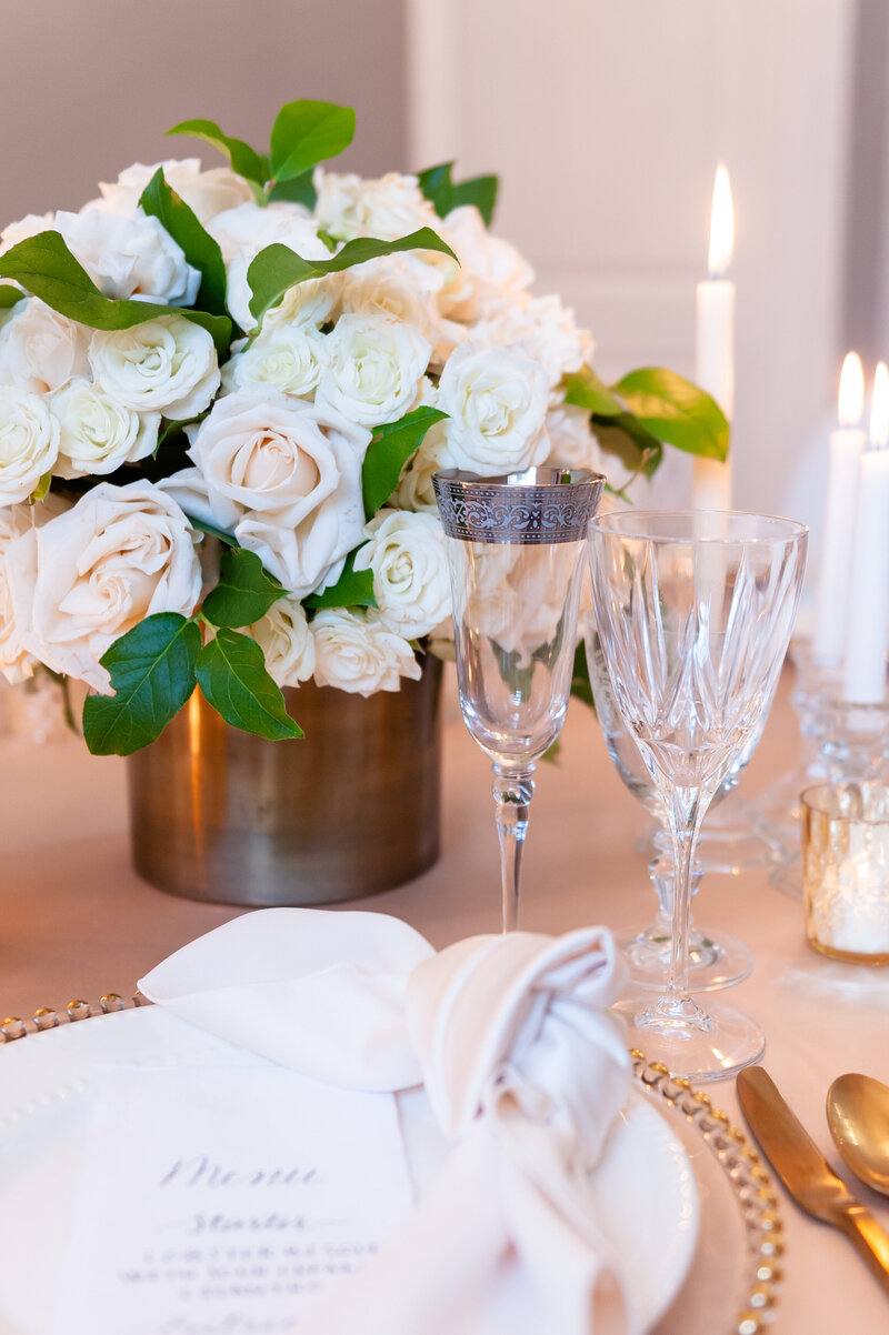 Luxury wedding reception decor featuring white floral centerpieces and fine tableware.