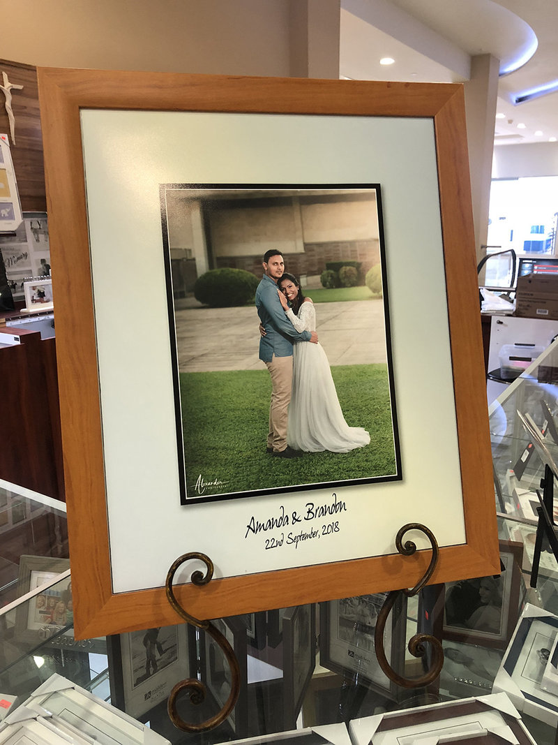 Sample of wedding picture with matt board for writing in medium brown wooden frame.. By Ross Photography TT.