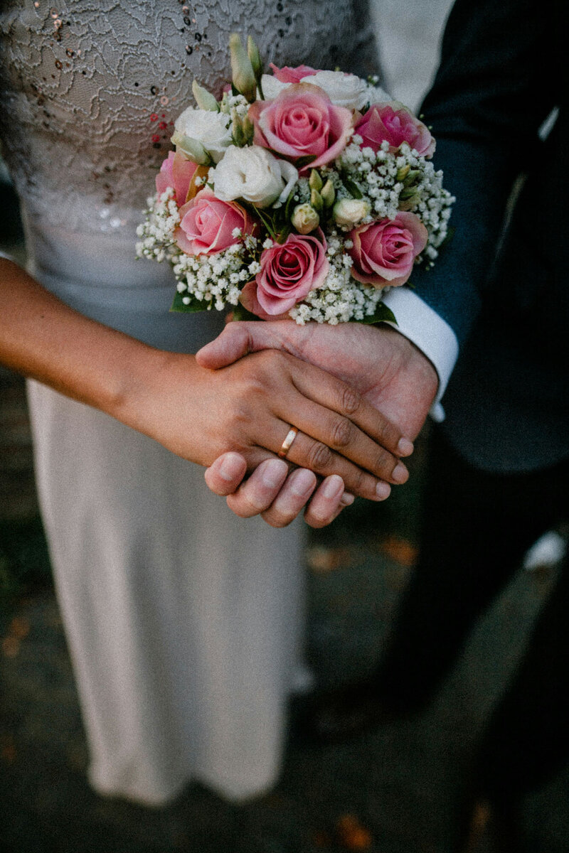 Bride and groom holding hands and the bride is wearing a wedding ring
