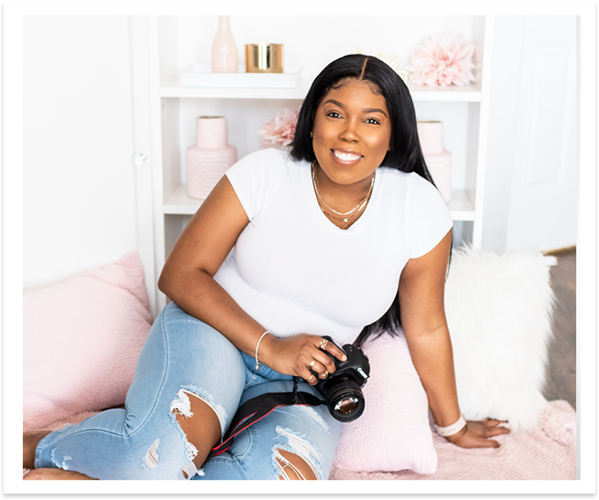 african american photographer sitting on a pink blanket and pillows with camera in hand