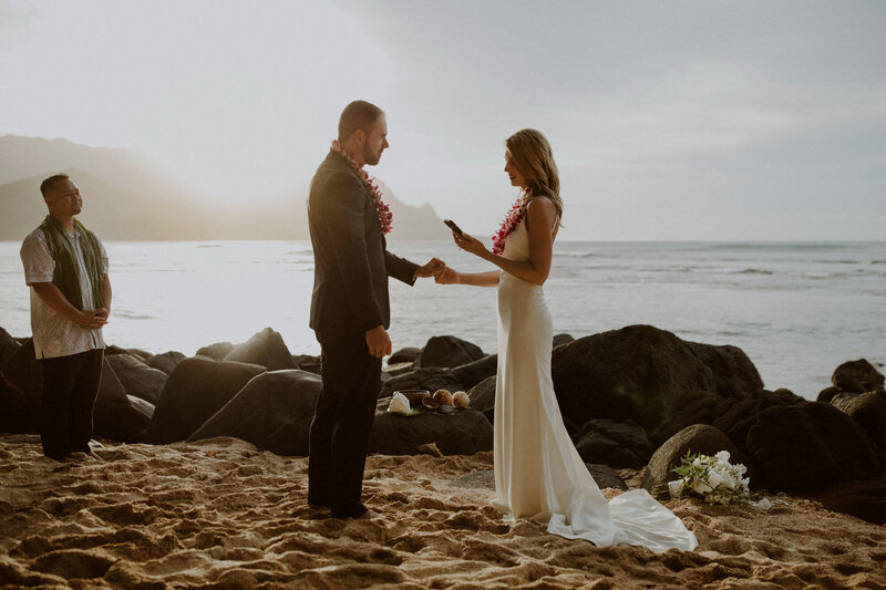 Bride and groom read vows on beach at sunset in Kauai