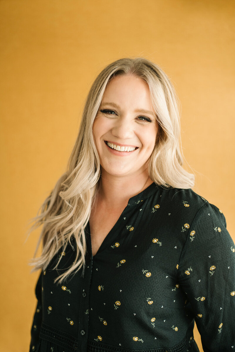 Jen isackson smiling at camera with yellow background