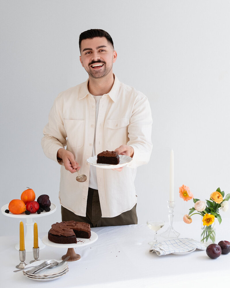 Eric King easygayoven leaning on a marble countertop in front of shelves filled with bakery items