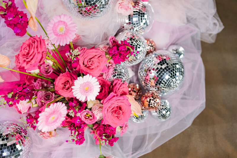 A close up view of flowers and mini disco balls sitting on lace.