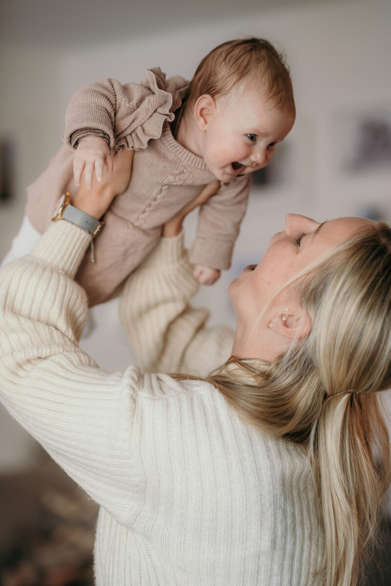 Mom holding her laughing baby up in the air - Newborn Photography Los Angeles Karin Busch.