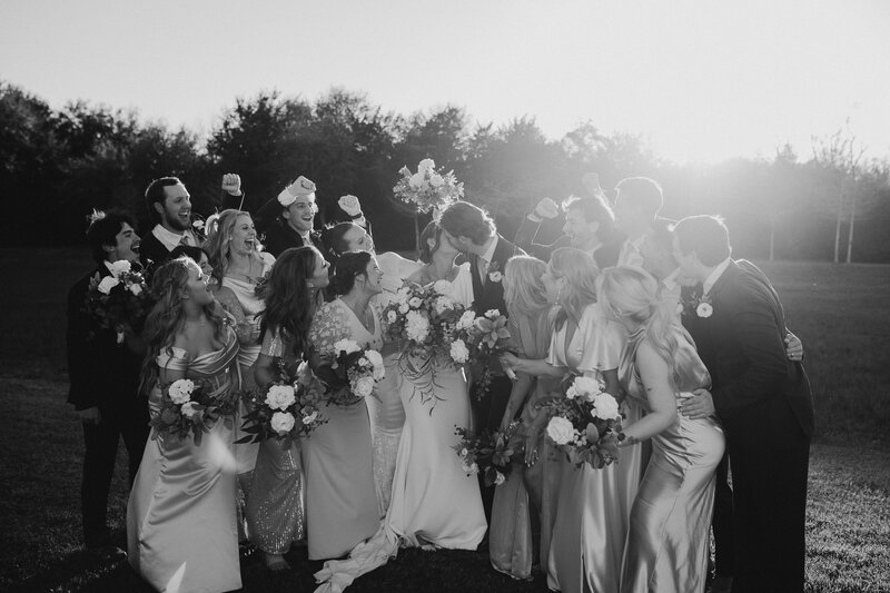 Bride and groom kiss with bridal party looking on