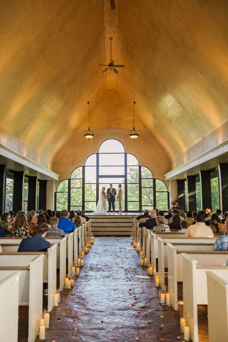 Natural light wedding ceremony in a glass chapel photographed by Claire Katan Creative in Omaha.