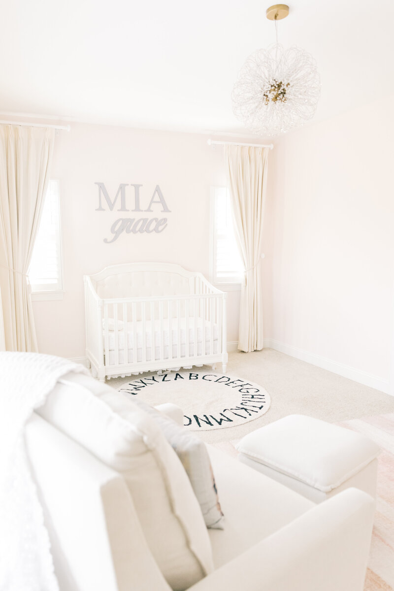 A crib sits between windows under a custom wall sign