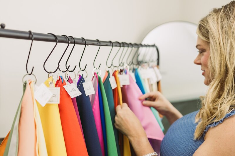 a woman sifting through cloths on a rack