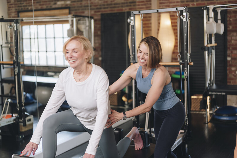 Pilates Mentors lead instructor assisting a client on a reformer 