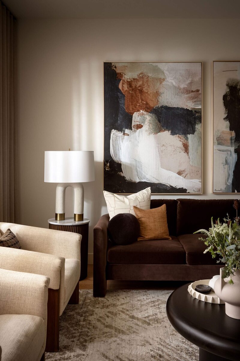 Large abstract art with arched accent lamps paired with chocolate and cream tones. 