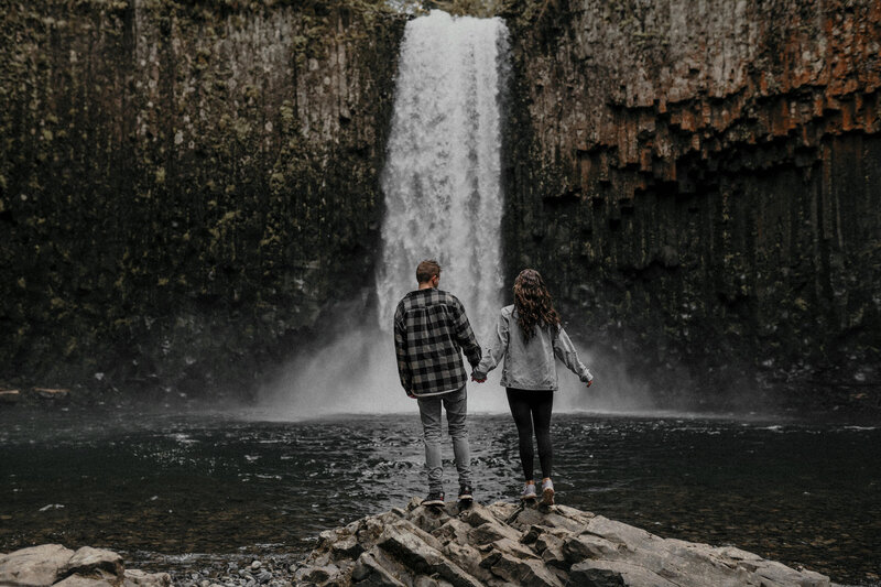 couple holding hands by waterfall
