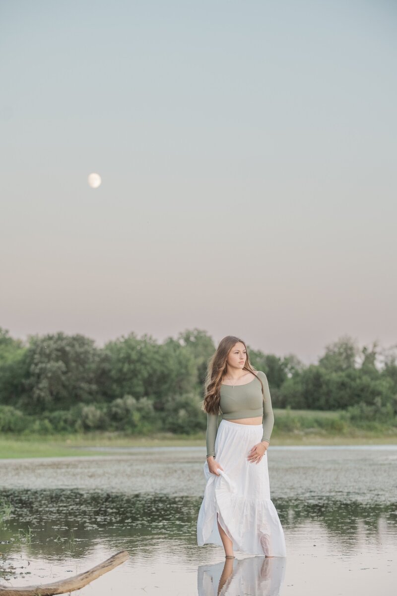 a girl in a dress standing in shallow water