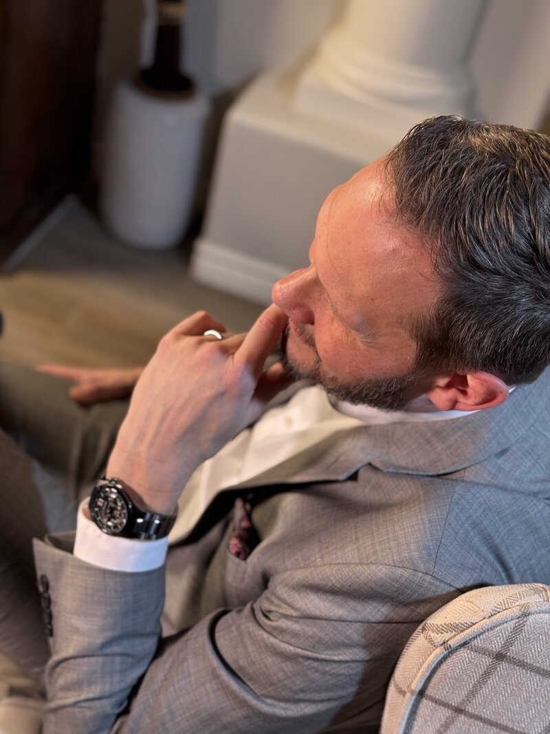 Top down view of middle-aged man listening with fingers on chin, leaning back in a chair in a conversation—symbolizing thoughtfulness. Ideal image for a Peace Coaching website promoting emotional wellness, stress relief, and personal growth