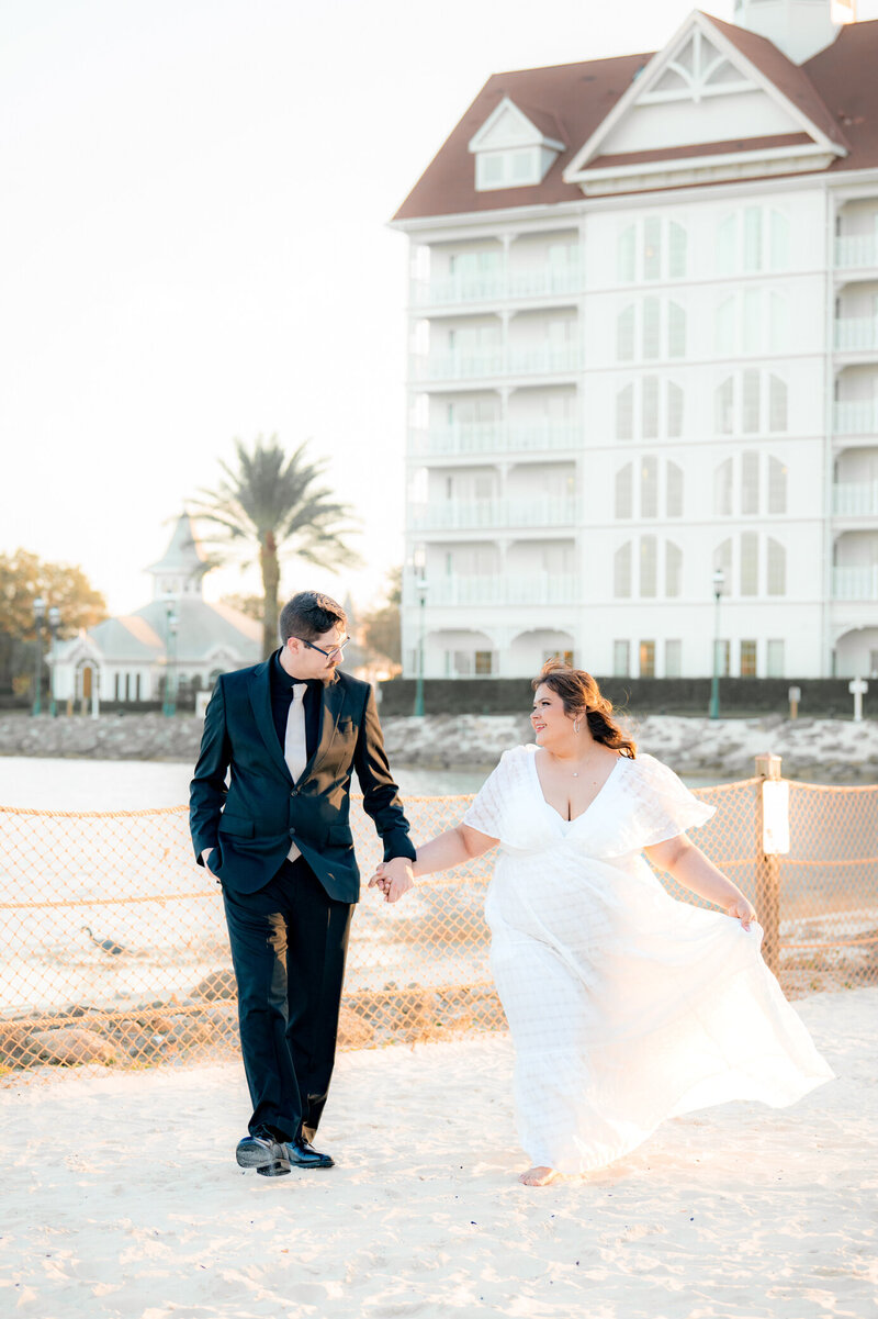 bride and groom walk hand in hand down beach in Orlando