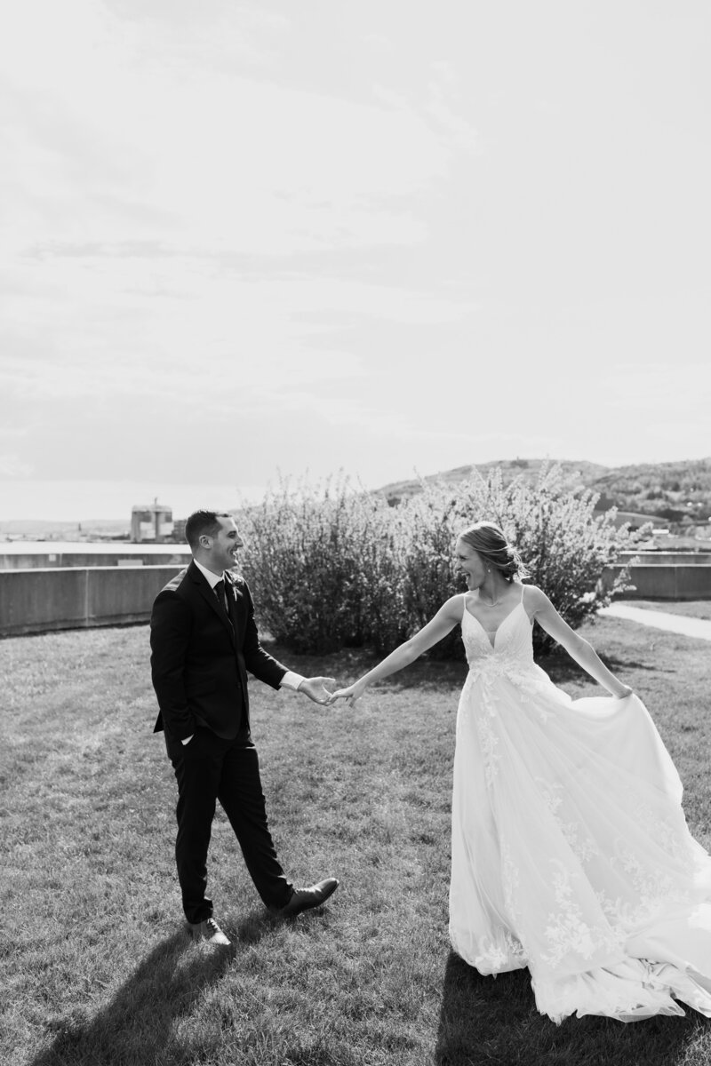 A newlywed couple holding hands and standing in a field 