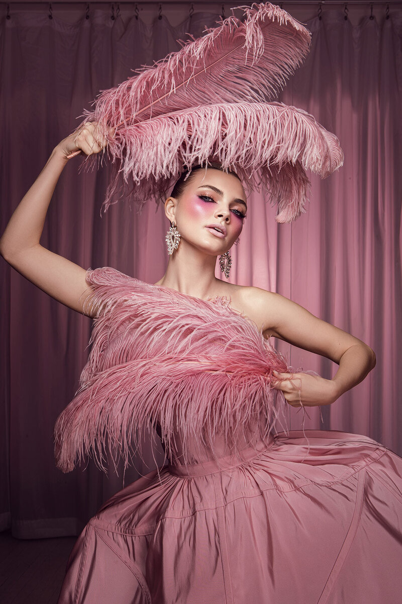 Playful portrait of Ashley in a pink ruffled outfit with a dynamic pose, captured by Ylva Erevall.