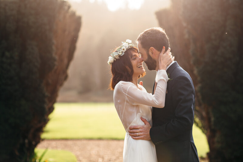 Couple who have eloped embrace in low winter sunshine