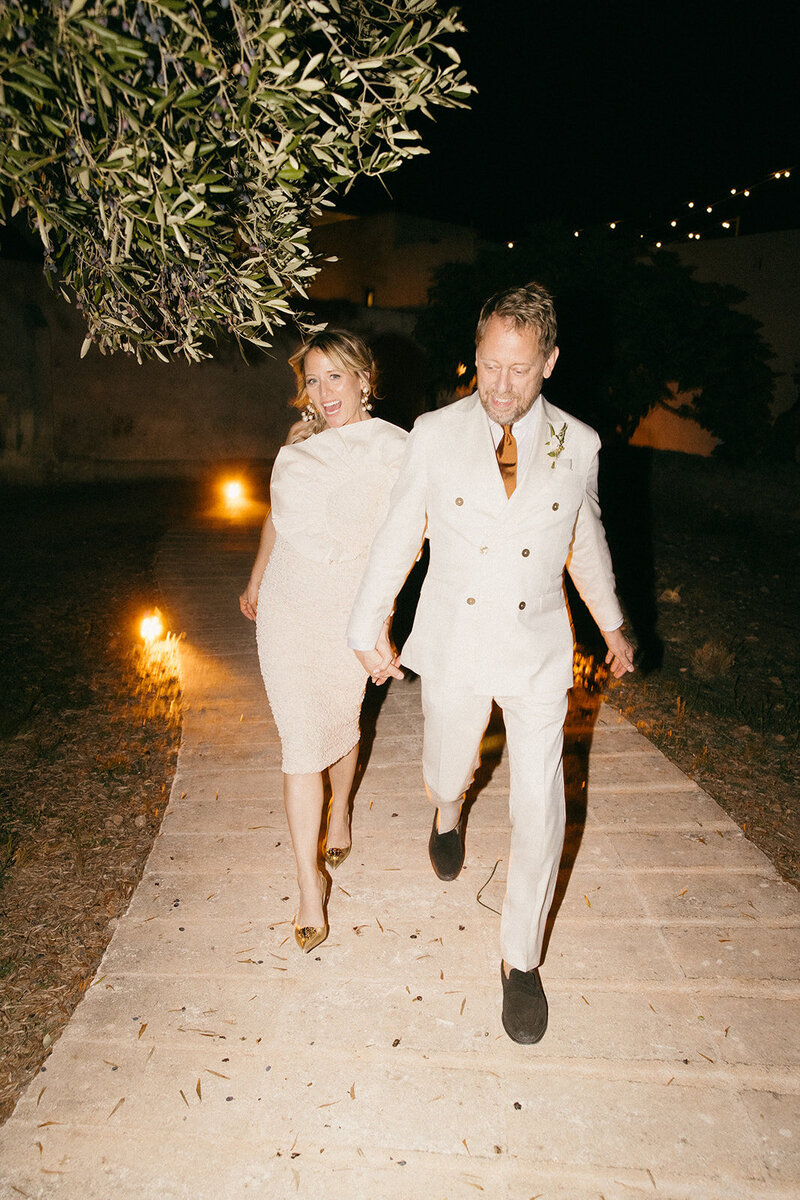 Carmen and Peter Settman walking to their dance party, dressed in white