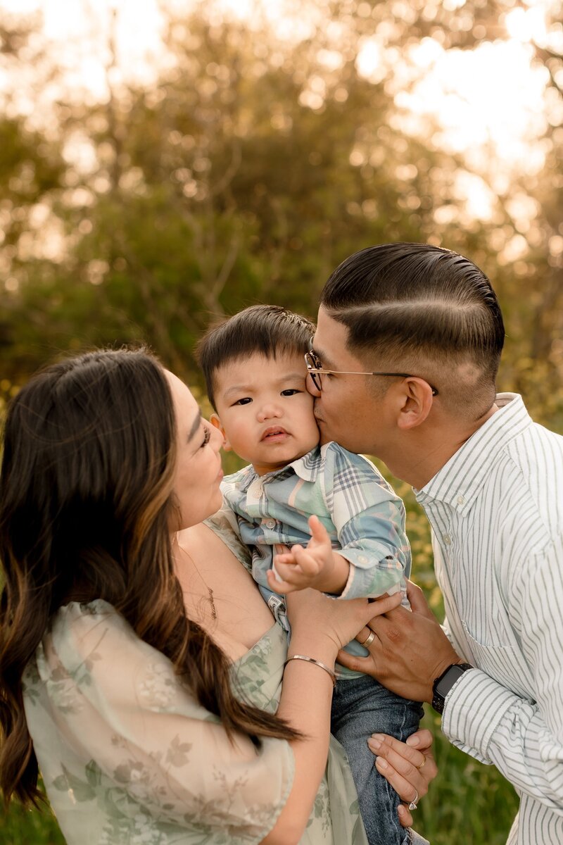 Mom and dad giving their son a kiss