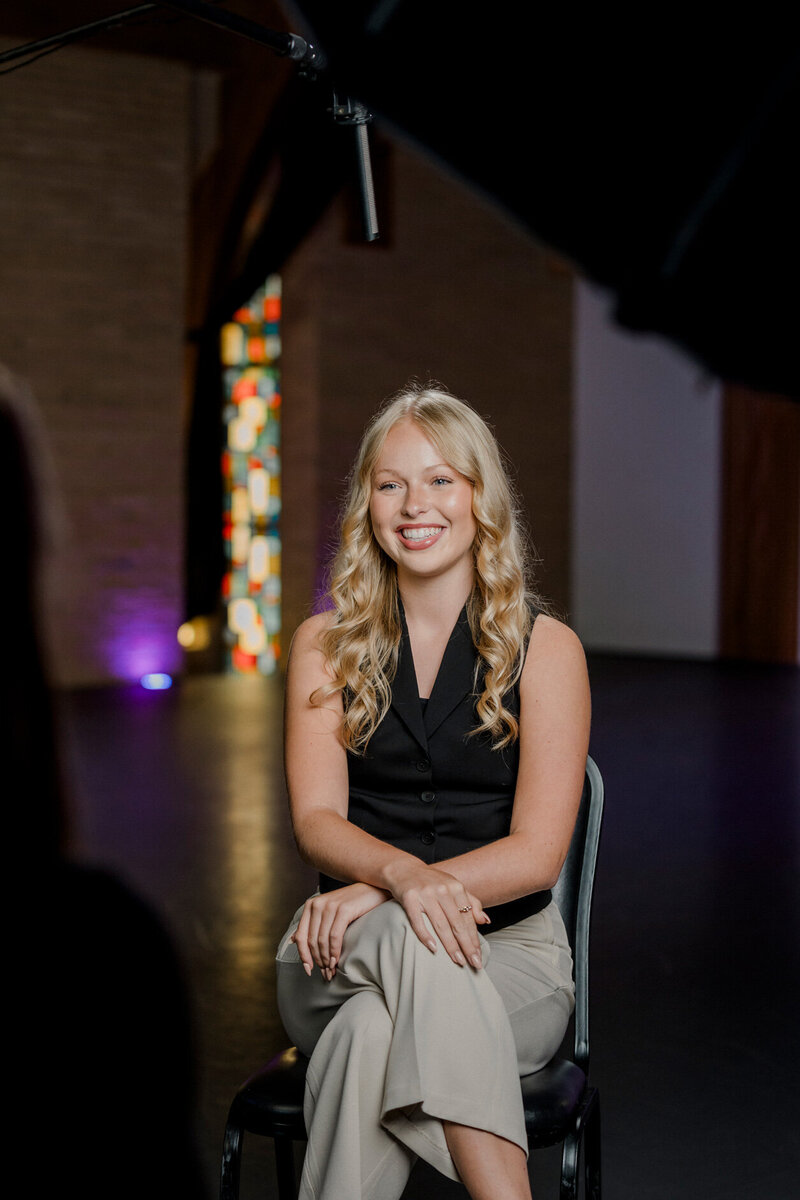 a woman smiles widely sitting under a boom microphone