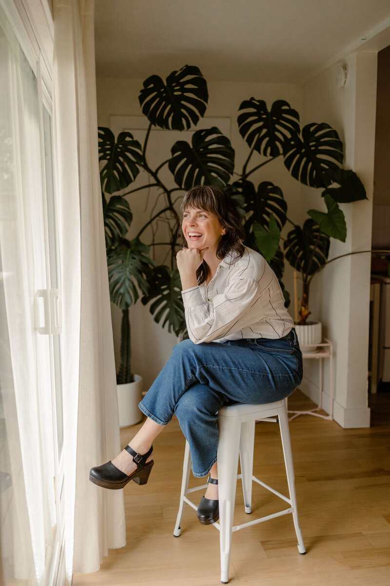 Web designer Carrie Bondioli smiles and sits on a stool