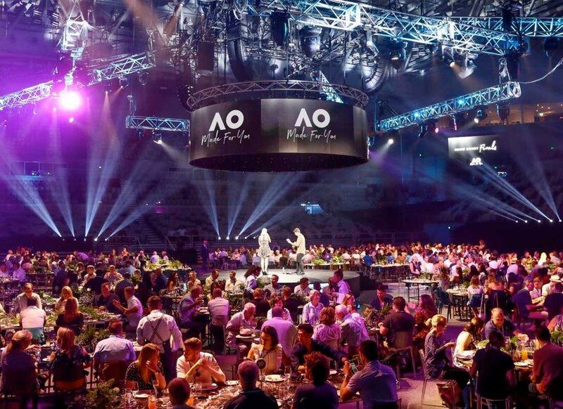 Australian Open hospitality event with live entertainment and seated dinner under dramatic stage lighting