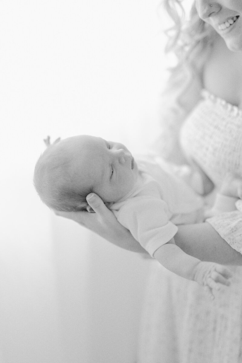 mother holding newborn son and smiling lovingly down in a seattle newborn photography studio