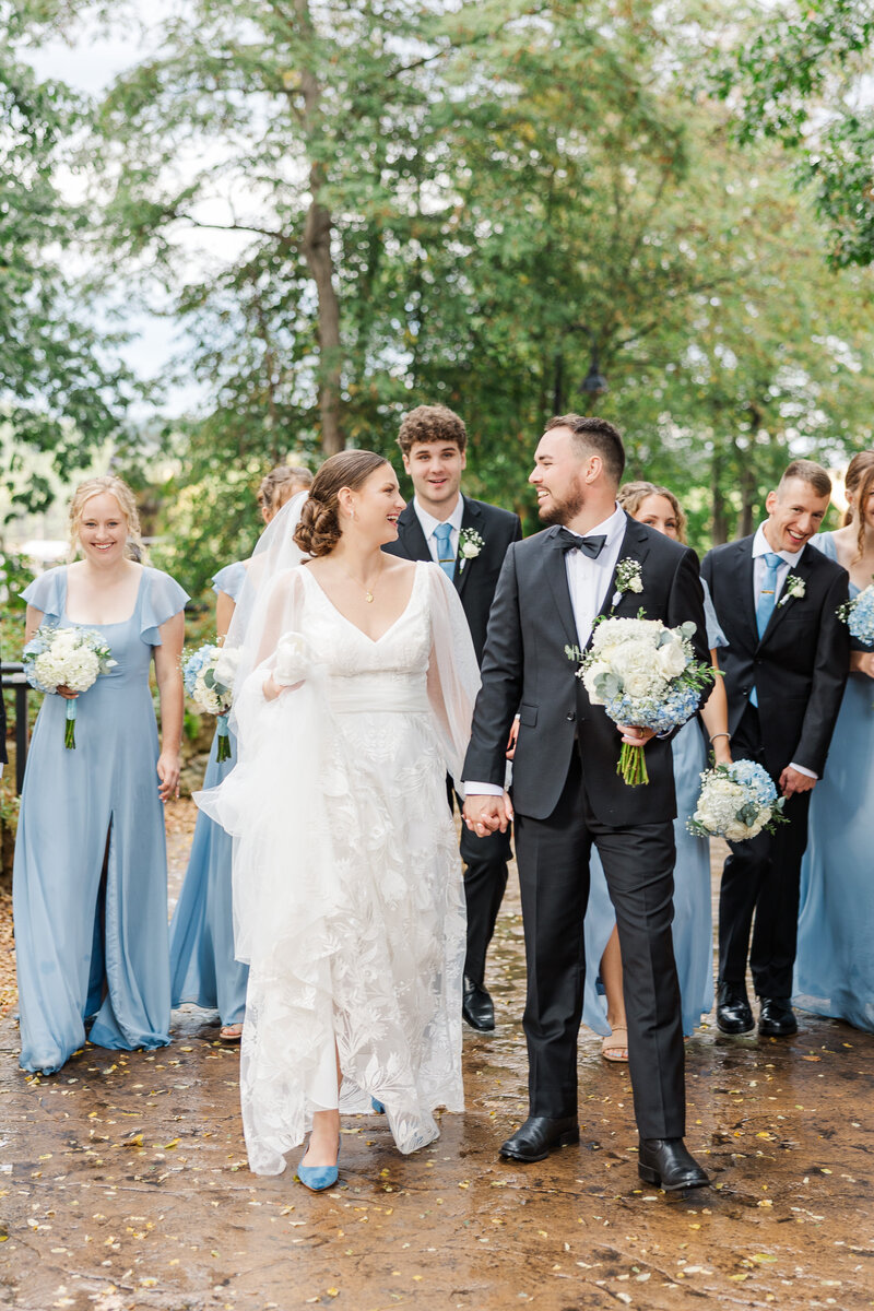 bride and groom holding hands while standing with their wedding party