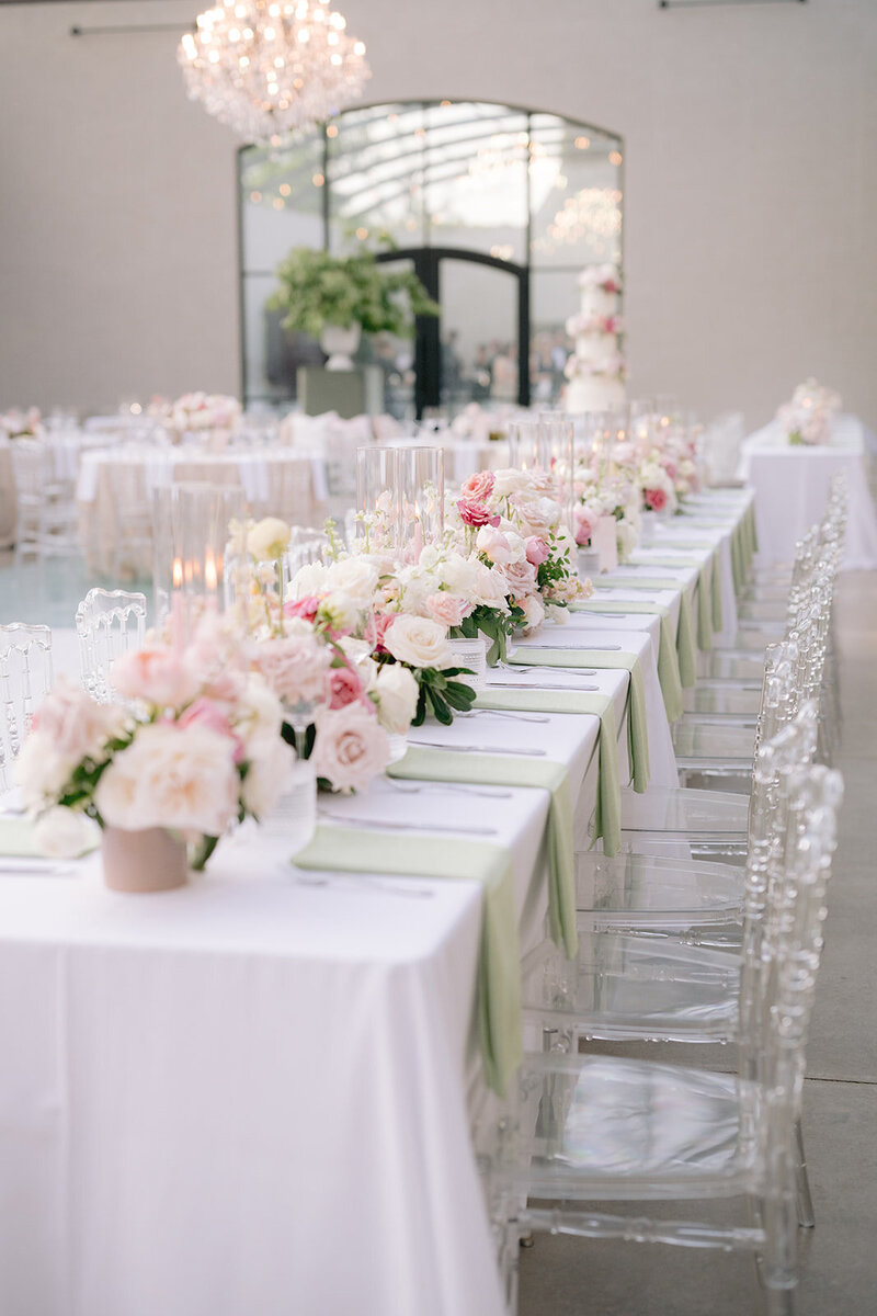 A room of tables with tall wedding floral arrangements