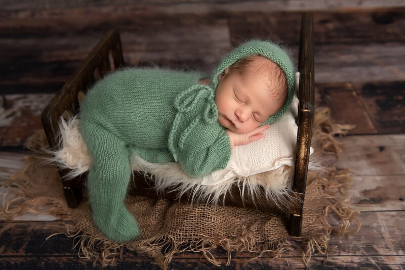 baby boy on newborn bed in green outfit