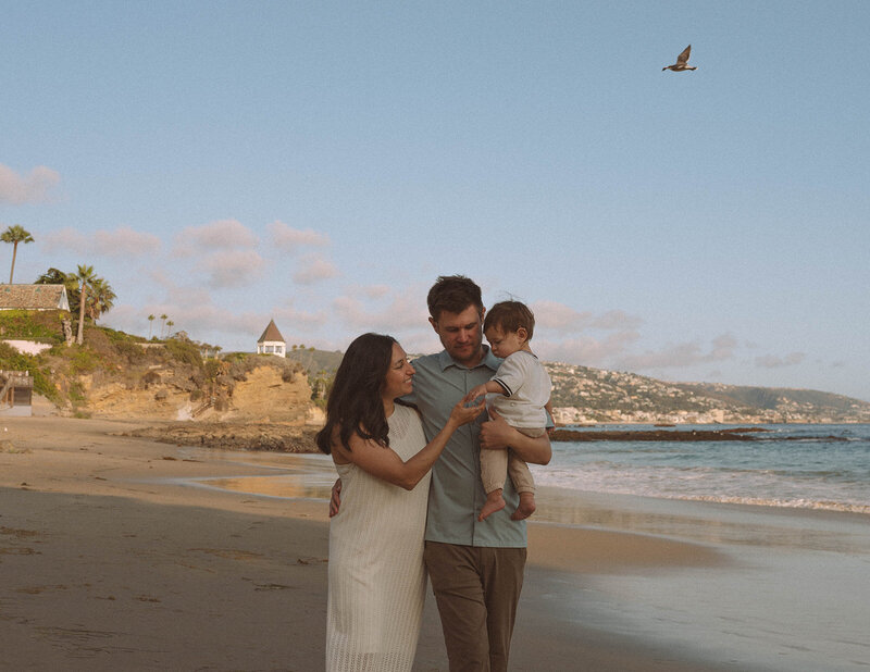 Family walking together along the shoreline at Shaws Cove in Laguna Beach during a relaxed Storyteller family photography session.