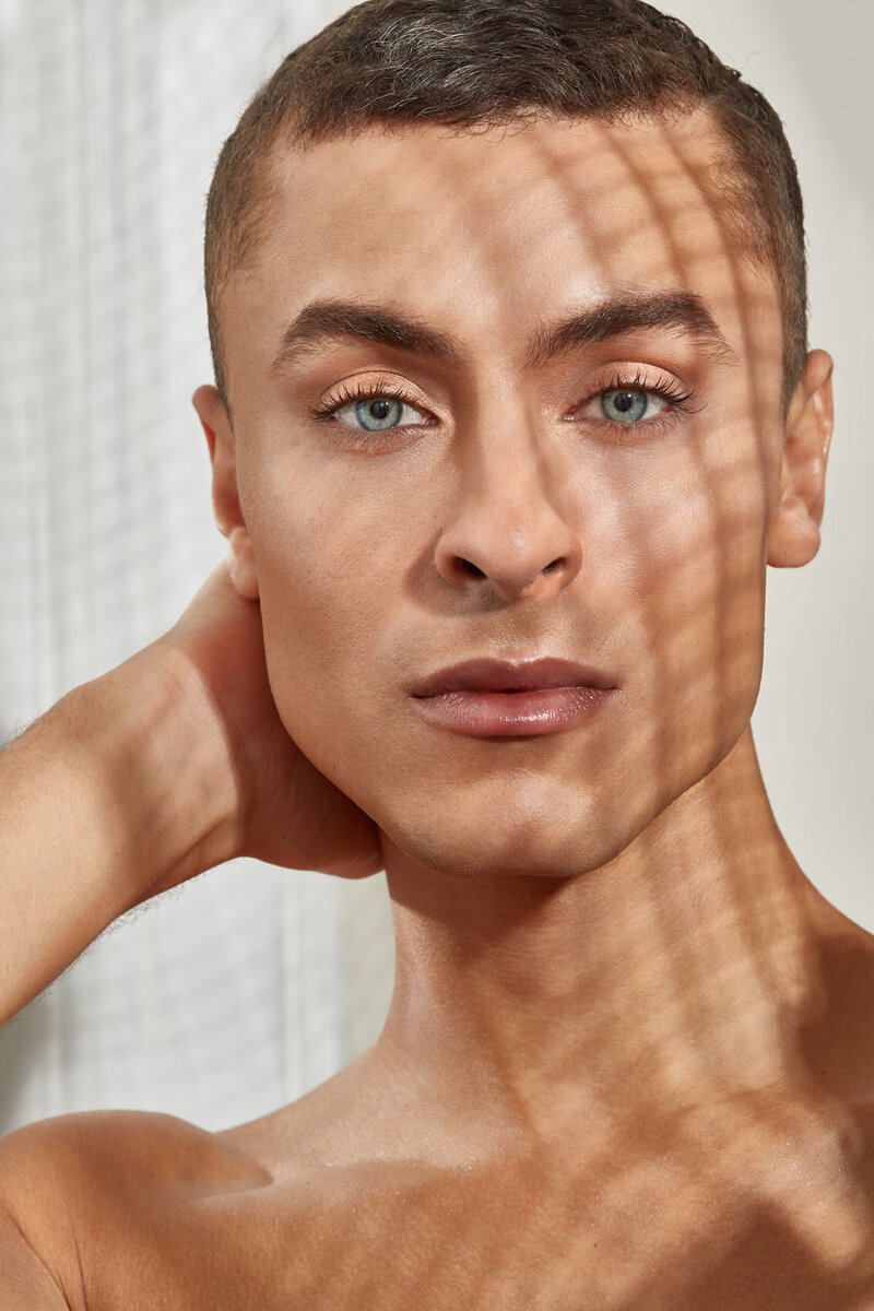 Artistic portrait of Cory with light and shadow patterns on his face, creating a striking visual effect, captured by Ylva Erevall.