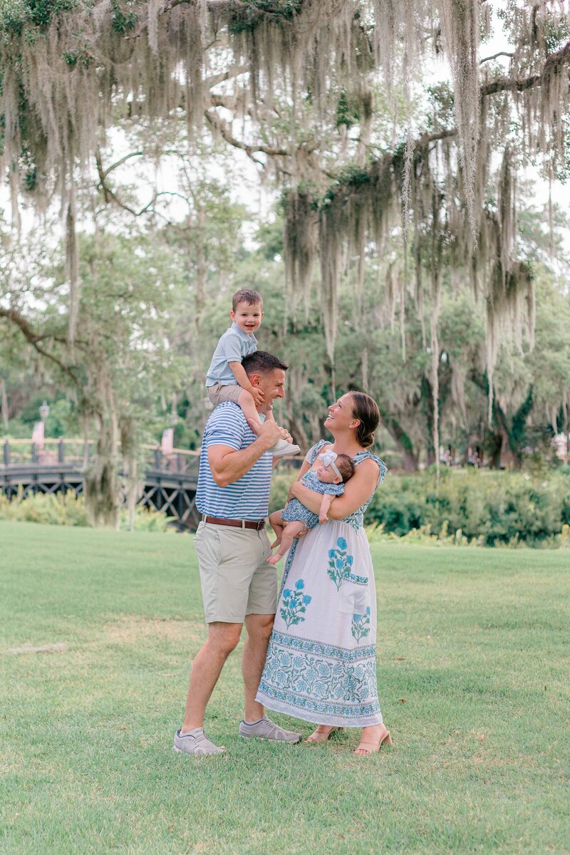 boy on dad’s shoulders, mom holding baby girl under oak trees for Palmetto Bluff photographer Lamp and Light Photography.
