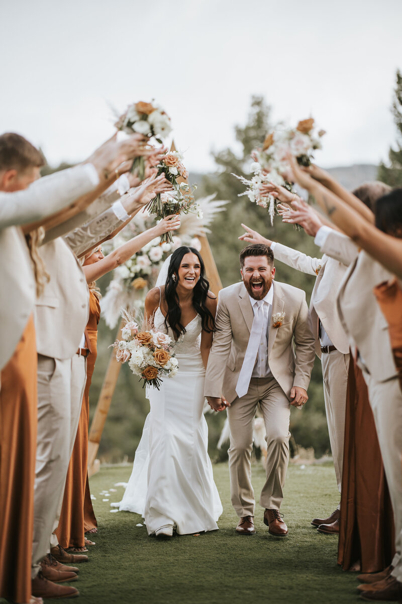 Newlywed couple shares a joyful moment in a lush forest.