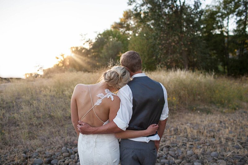 Newlyweds holding each other and looking at sunset