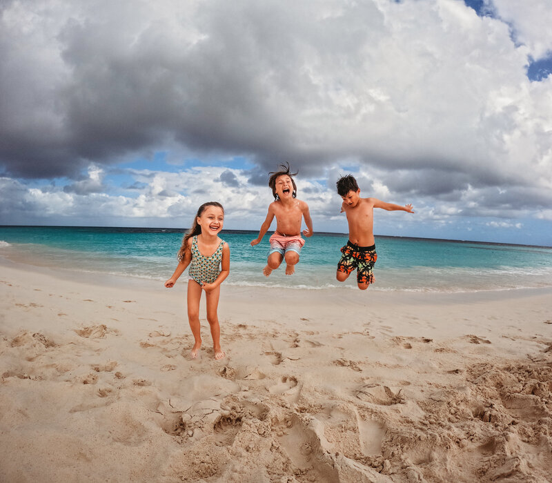 Siblings happy and jumping on beach taken by family photographer Candice Berman Photography