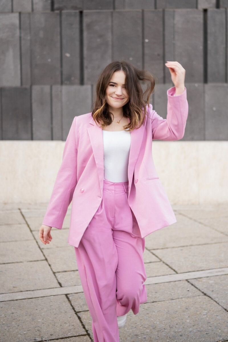 Picture of the Shapely Studio founder in a pink suit, walking towards the camera