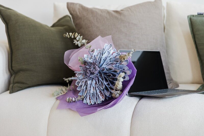 Hailey Ann Co Bookkeeper and somatic money coach for female entrepreneurs. Money Bouquet and laptop on couch