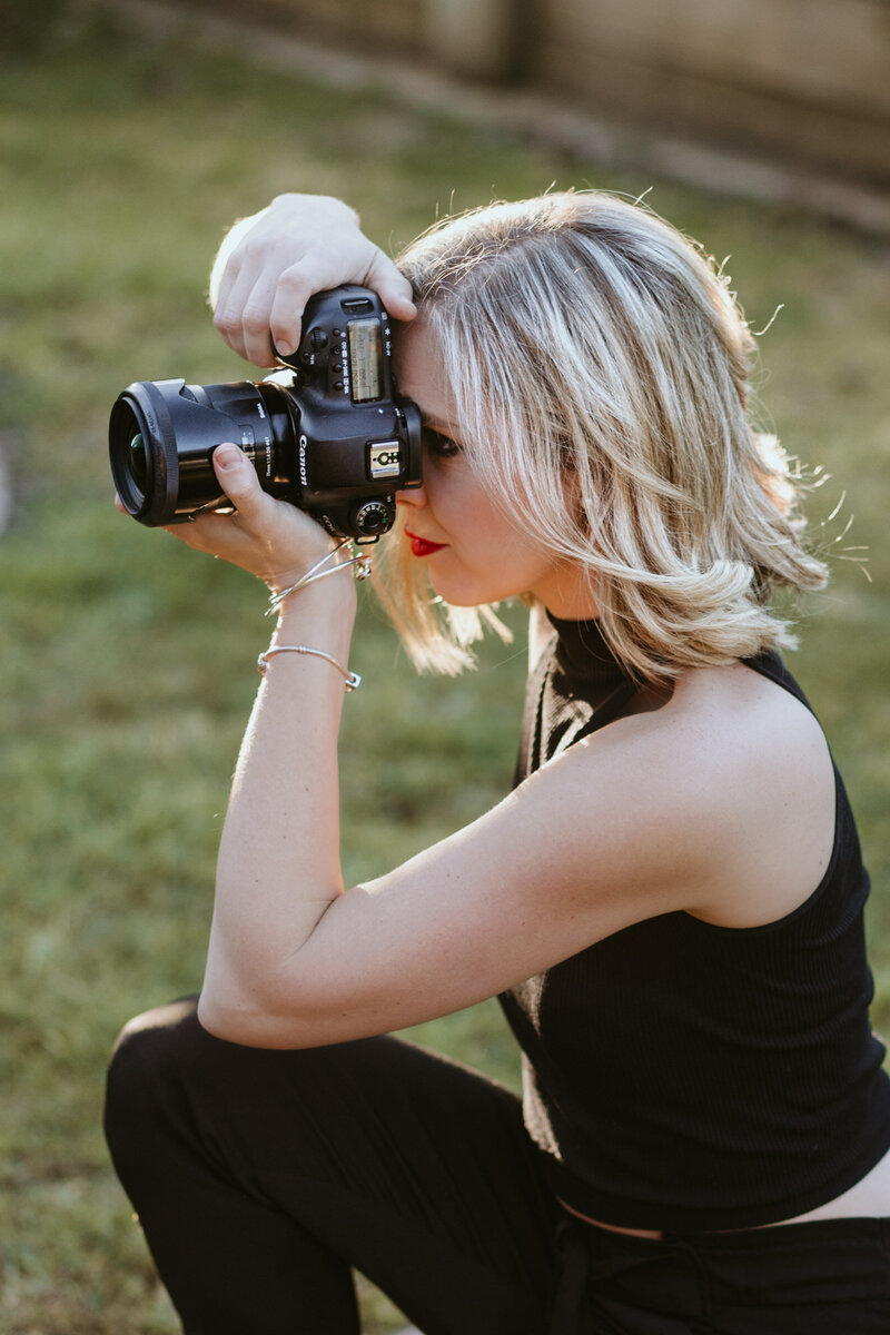 Tanya Strauss kneeling with camera in hand, working as a Bendigo wedding and portrait photographer