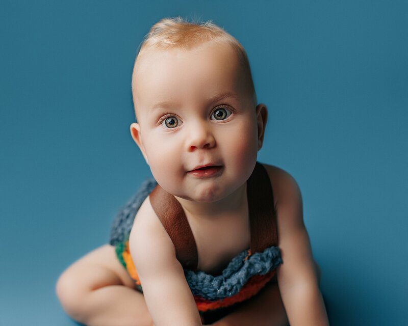 Baby reaching forward and smiling brightly in natural light studio
