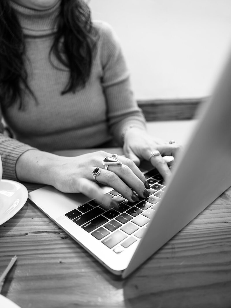 Faceless woman typing on a laptop, representing Bloem Creations' offering of copywriting services. 