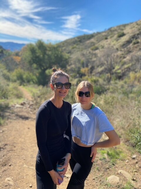 Devon and her niece hiking in the mountains on a sunny day.