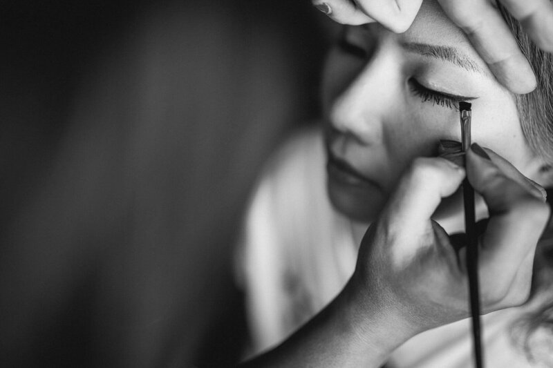 A black and white photo of a bride having her makeup done