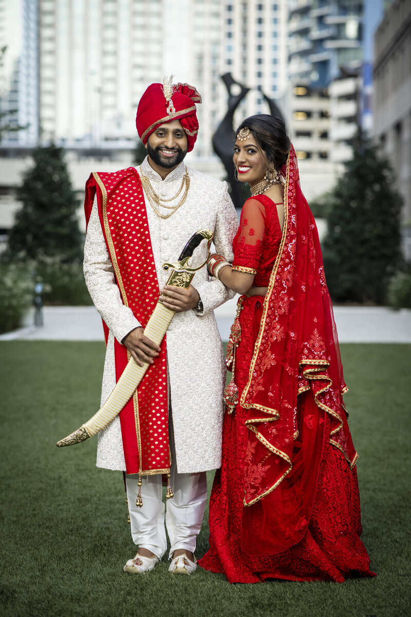 Indian bride and groom stand in front of Founder's Hall.