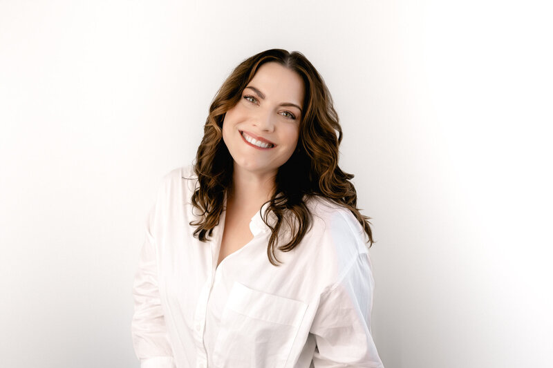 A woman in a white shirt smiling at the camera.